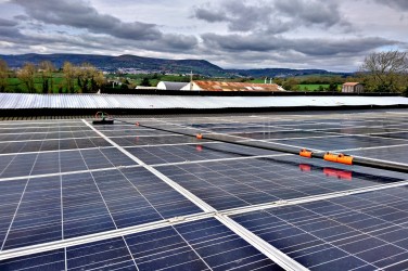 Solar panels on the roof of a building against a backdrop of fields